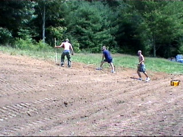 {The guys rakeing the yard}